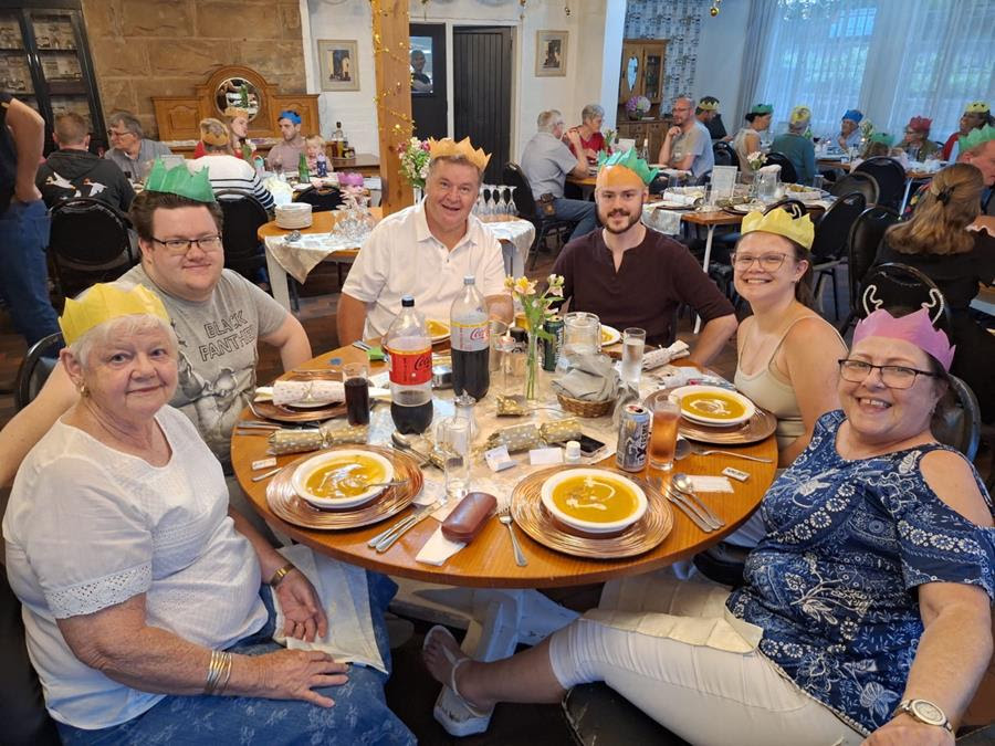 Guests wearing colourful paper crowns around a Christmas lunch table at Wyndford