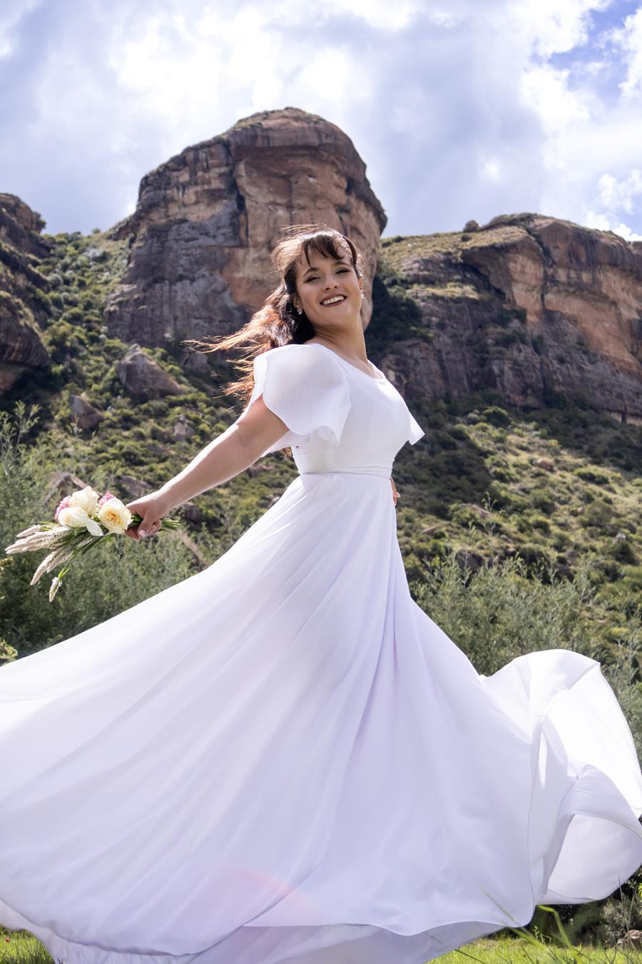 A bride holding a bouquet in front of sandstone cliffs at Wyndford