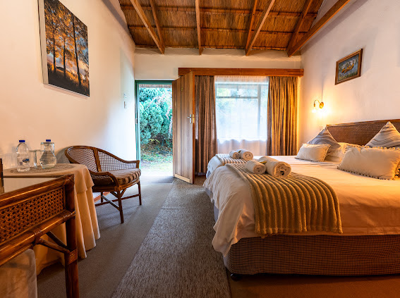 Wyndford guest room with a thatched ceiling, white bed linen and a door opening to the garden